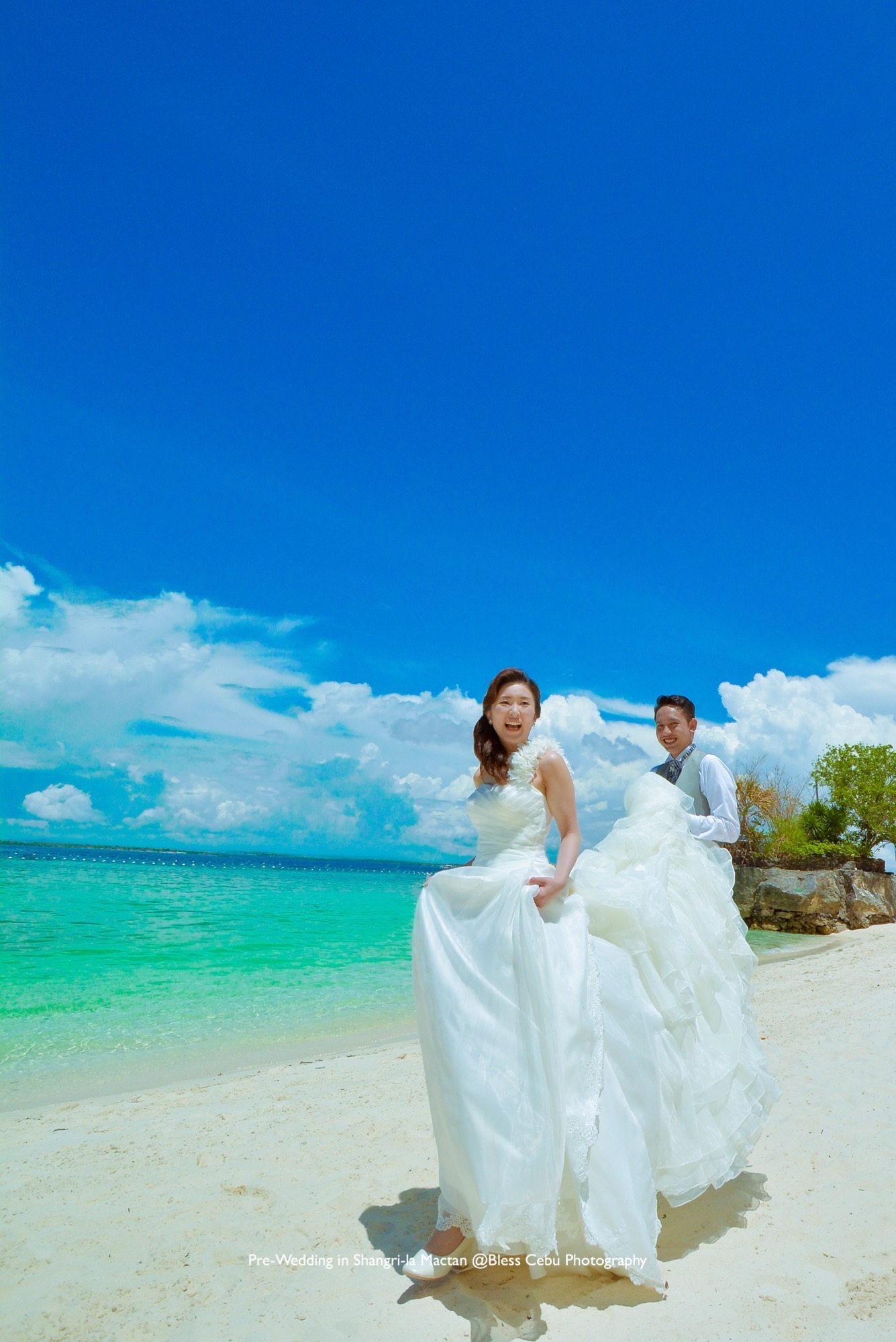 コーラルブルーのビーチで、眩しい笑顔の花嫁花婿
