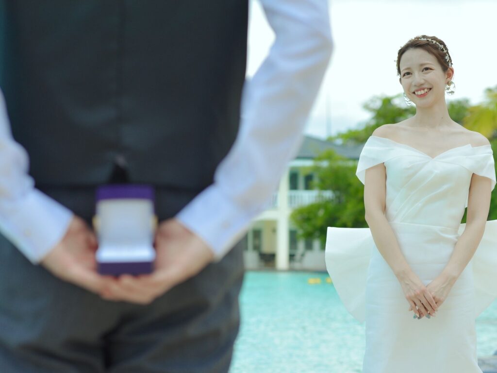 背中に婚約指輪を隠す新郎と笑顔の花嫁の前撮りサプライズショット