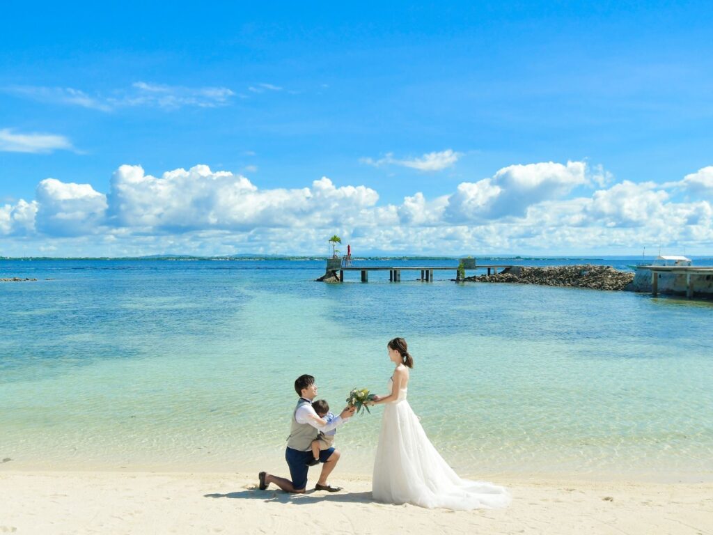 ビーチでひざまずきプロポーズする新郎と花嫁の前撮り写真