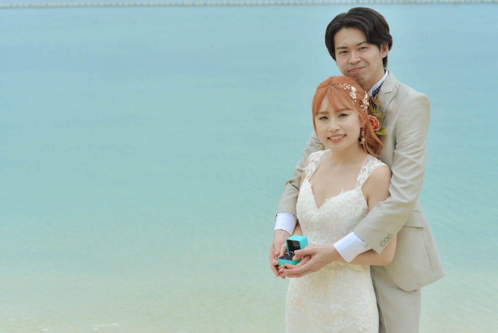 セブ島ブルーウォーター・マリバゴの海を背景にリングボックスを手に微笑む新郎新婦のビーチフォト
